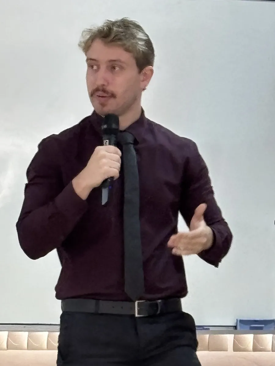 Dr. Diogo Carlos, advogado, de camisa vinho e gravata preta, em palestra