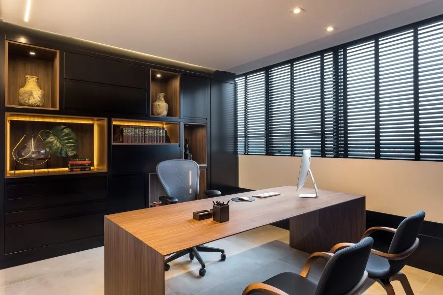 Sala de atendimento do escritório, com mesa de madeira e estante iluminada